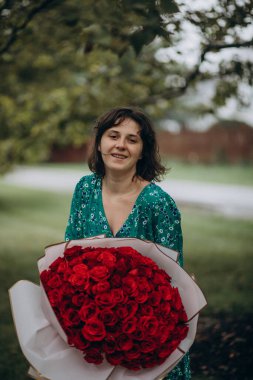 Saçında kırmızı güller olan güzel bir kadın.