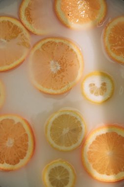Limonlar ve portakallar sütle dolu bir kasede