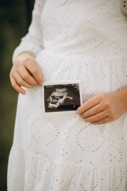 Elinde beyaz bir kalp tutan hamile bir kadın. yüksek kaliteli fotoğraf