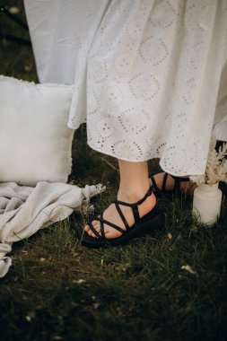 Gelinin ayaklarının beyaz havluyla yakın plan fotoğrafı ve bir buket beyaz çiçek.