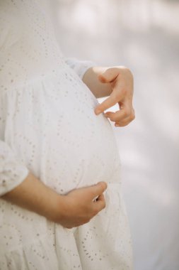 Annenin elini tutarak hamile karnını kapat.