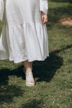 Beyaz elbiseli, beyaz elbiseli, yerde yürüyen güzel bir gelinin dikey görüntüsü.