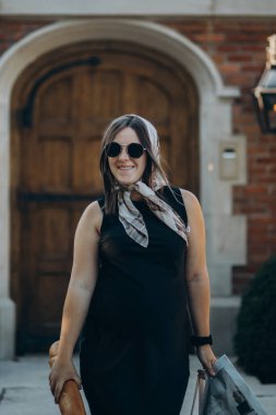 Güzel, genç, esmer, siyah elbiseli bir kadın sokakta poz veriyor..