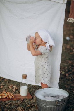 Beyaz elbiseli, elinde bir şişe süt ve pipetle küçük bir kız. Sağlıklı beslenme, sağlıklı beslenme ve beslenme kavramı. Kız.