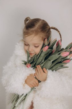 Çiçek buketiyle beyaz önlüklü şirin bir çocuk. Bahar çiçekleri yüksek kaliteli fotoğraf
