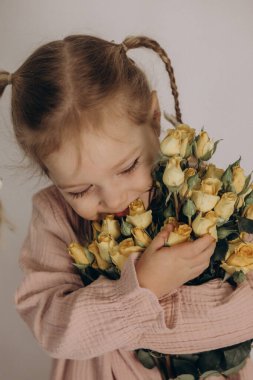 Bir buket çiçekli elbise içindeki küçük kız