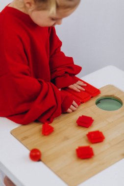 Bir çocuk kırmızı ve yeşil bir oyuncak yapıyor..