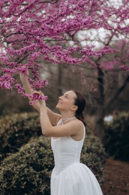 Parktaki ağacın yanında poz veren güzel genç bir kadın.