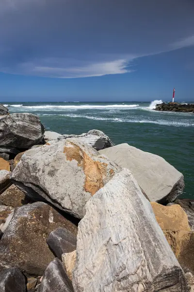 Big rocks and ominous storm clouds in sky over water at breakwall on Wooli Wooli River