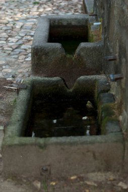 Stone fountain with moss with little water due to drought in summer, vertical