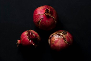 Açık kırmızı olgun nar, siyah arka plan görünümünde yemeye hazır.