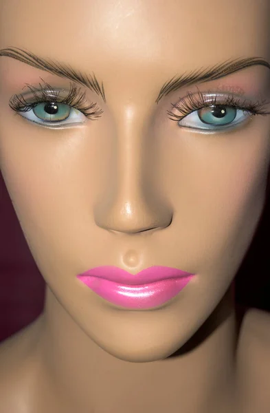 Woman mannequin face with nose, mouth and lips painted pink, blue eyes vertically