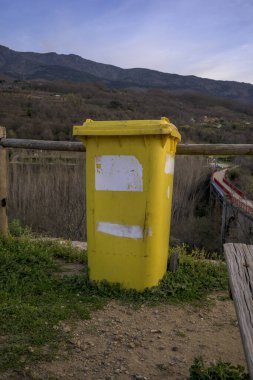 Plastik ve geri dönüşüm için sarı konteynır ve doğadaki bir dağ bölgesine çöp atmak için değil.