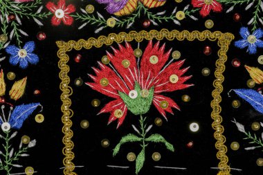 Gül, yaprak ve parlak pullarla işlenmiş bölgesel halk kostümünün ayrıntıları