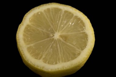 Koyu siyah arkaplanlı yarı sarı limon yatay olarak Citrus aurantifolia