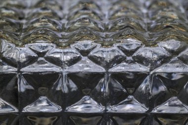 Cam içki şişesinin kenarı yatay olarak aydınlatılmış kare altıgenler oyulmuş.