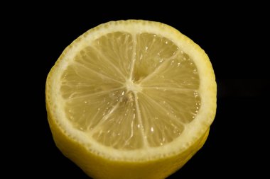 Yatay olarak siyah arkaplanlı, taze sarı bir limon.