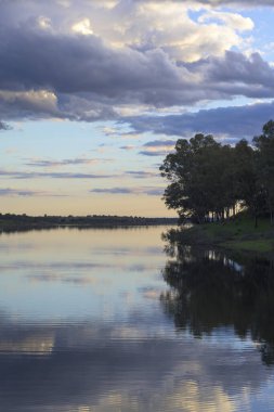 Ağaçların yansımaları mavi gökyüzü, ve suyun içindeki bulutlar dikey dalgalar