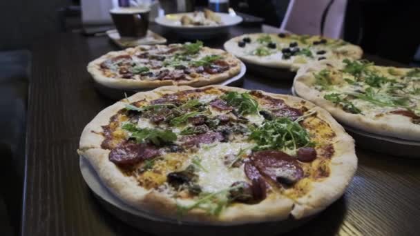 ピザ屋のテーブルの上のピザの多くは クローズアップ ベーコン ペパロニ チーズなどのイタリアのピザをレストランですぐに食べることができる多くのパンショット 様々な種類のピザ — ストック動画