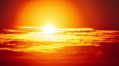 Ufuktaki turuncu gökyüzünde yumuşak bulutlar arasında dramatik bir gün batımı. Güneş ışığıyla birlikte büyük parlak kırmızı güneş aşağıya doğru hareket ediyor. Müthiş destansı bulut uzayı, canlı bir renk. Zaman aşımı. Sarı Gökte Gün Batımı