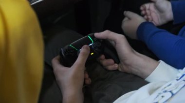Oyun konsolunda oyun. Genç bir masada otururken elinde bir joystick 'i kontrol ediyor, yakın plan. Çocuk, eğlence merkezinin oyun sahasında oyun kumandası kullanıyor. Oyun oynayan oyuncu
