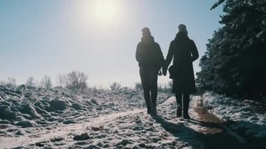 İki kız kış ormanında el ele yürüyorlar. Yavaş çekimde, dikiz aynasıyla. Parlak güneşe karşı kar yolunda yürüyen kadın kız arkadaşlar. Sevgi dolu bir çift adımın arka görüntüsü. LGBT, lezbiyen