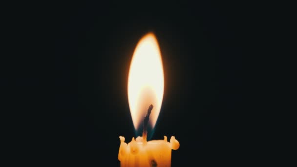 一根蜡烛在黑色的背景上燃烧 黄色闪烁的火焰的特写照亮了黑暗 孤立无援 科皮斯炽热的火光随风飘扬 — 图库视频影像