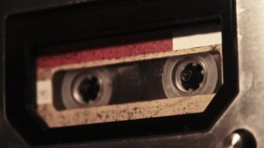 Retro bir teypte ses kaydı oynatılıyor. Plak çalar, yanıp sönen mum ışığında eski sarı bir kaset çalar, yakın plan. Eski bant makaraları güvertede dönüyor. Arama kaydı, çalma, 80 'ler