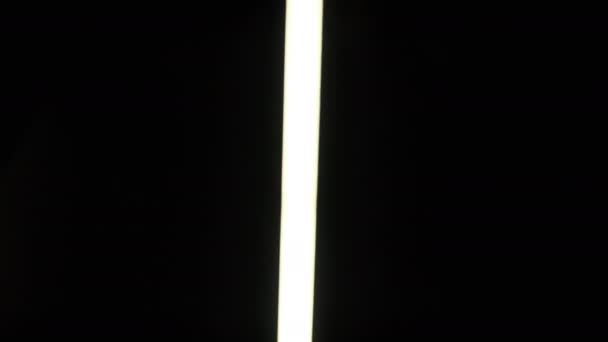 Led剣 白い懐中電灯の側から側に黒の背景に移動します 写真効果 スワイプします ネオン管の長い提灯が明るく輝いています ネオン背景蛍光灯 — ストック動画