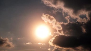 Turuncu bulutların arasından gökyüzünde güneş ışınlarıyla dramatik günbatımının zamanı. Büyük parlak turuncu güneş ufukta aşağı doğru hareket ediyor. Müthiş destansı bulut uzayı, canlı bir renk. Zaman aşımı. Gün batımı. 4K