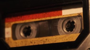 The cassette is played in a tape recorder in soft flickering candlelight, close-up. Yellow audio cassette in the deck rotates. Vintage sound recording in an old retro recorder. Audio Cassette playback