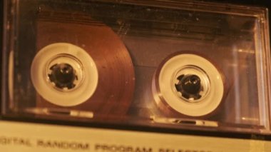 Klasik kayıt cihazında ses kasedi oynatıcısı. Eski şeffaf ses kasedini çalan bir pikap, yakın plan. Retro bantlar güvertede dönüyor. Konuşmalar kaydediliyor, 80 'ler, arşiv kaydı, çağrı