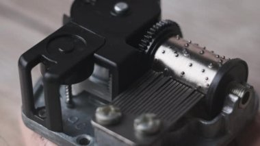 Music box mechanism close-up. Old music box clockwork device on spinning cylinder and cogs. Retro rotating drum with projections touching the records creates music. Toy barrel organ rotates. 4K