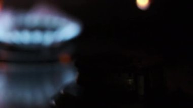 Ignite the gas on the stove with a match close-up. Manual ignition of the gas burner in a home kitchen. Burning blue flame of natural gas, macro. Burner operation, Fire on the stove. Circular gas-jet