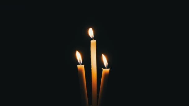 三支蜡烛在黑色的背景上燃烧 孤立的黄色闪烁着的火焰的特写照亮了黑暗 科皮尼斯 烛焰的温暖之火随风飘扬 文字的位置 — 图库视频影像