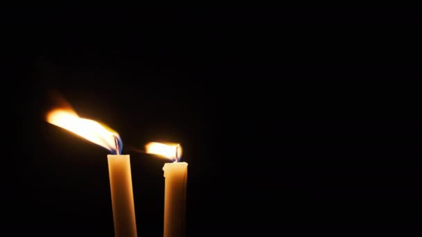 两支蜡烛在黑色的背景上燃烧 一支黄色摇曳的蜡烛照亮了黑暗 概念记忆 宗教或庆祝活动 炽热的火光摇曳着 孤立无援的科皮尼斯 — 图库视频影像