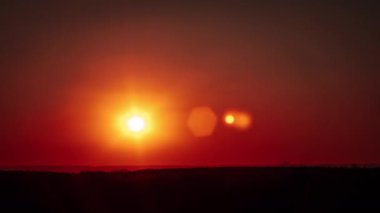 Gün batımının zamanı ufukta turuncu gökyüzünde parlayan mercekle. Güneş ışığıyla birlikte büyük parlak kırmızı güneş aşağıya doğru hareket ediyor. Müthiş destansı bulut uzayı, canlı bir renk. Zaman aşımı. Sarı Gökte Gün Batımı