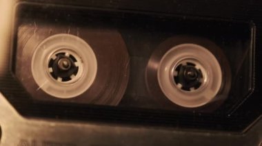 Retro bir teypte ses kaydı oynatılıyor. Plak çalar titreyen mum ışığında eski şeffaf bir ses kaseti çalıyor, yakın plan. Eski bant makaraları güvertede dönüyor. Kaydı ara, oynat