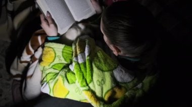 Bir kadın, geceleri bir el fenerinin ışığında kanepede yatan bir kitap okur. Sabahlık ve rahat bir oda giymiş bir kız kitap okumakla meşgul. Sıcak, sıcak bir oturma odasında fener ışığının tadını çıkarıyorum..