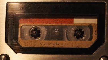 The cassette is played in a tape recorder in soft flickering candlelight, close-up. Yellow audio cassette in the deck rotates. Vintage sound recording in an old retro recorder. Audio Cassette playback