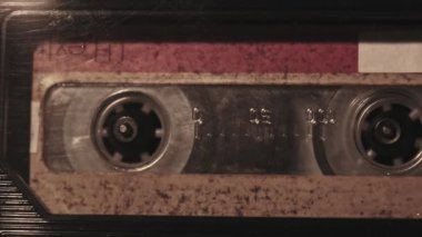 The cassette is played in a tape recorder in soft flickering candlelight, close-up. Yellow audio cassette in the deck rotates. Vintage sound recording in an old retro recorder. Audio Cassette playback