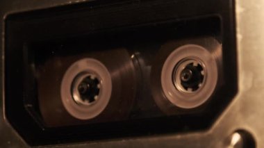 Retro bir teypte ses kaydı oynatılıyor. Plak çalar titreyen mum ışığında eski şeffaf bir ses kaseti çalıyor, yakın plan. Eski bant makaraları güvertede dönüyor. Kaydı ara, oynat