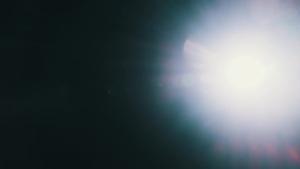亮手电筒的点灯指向黑色背景上的相机 从侧面到侧面的光的抽象运动 光在镜片中反射的效果 灯火辉煌 灯火通明 — 图库视频影像