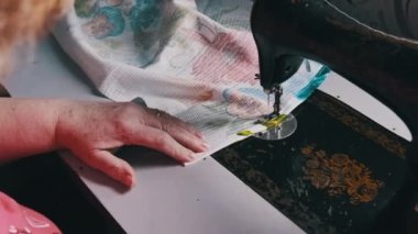 Grandmother sews on vintage sewing machine at home in slow motion. Close-up of the steel sewing machine needle quickly moves up and down. Old female hands of seamstress sewing fabric. Lifestyle, hobby