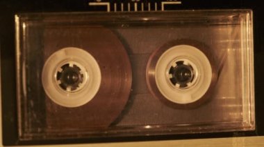 Klasik kayıt cihazında ses kasedi oynatıcısı. Eski şeffaf ses kasedini çalan bir pikap, yakın plan. Retro bantlar güvertede dönüyor. Konuşmalar kaydediliyor, 80 'ler, arşiv kaydı, çağrı