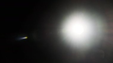 The light of a bright flashlight directed at the camera moves from side to side. Light effect of reflections in lenses. Flashes of blue light, effect. Transition, lens flare, light leaks. 4K