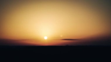 Timelapse of sunset in the orange sky over the horizon. Big bright red sun with sunrays moves down. Awesome epic cloud space, vibrant color. Time Lapse. Sundown in Yellow Sky