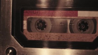 Retro bir teypte ses kaydı oynatılıyor. Plak çalar, yanıp sönen mum ışığında eski sarı bir kaset çalar, yakın plan. Eski bant makaraları güvertede dönüyor. Arama kaydı, çalma, 80 'ler