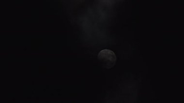 Gece gökyüzündeki dolunay kara bulutların arasında parlıyor. Mistik ay ışığı. Ayın önünden geçen gerçek karanlık ve gizemli bulutlar. Kara fırtınalı bulutlar ve ay.