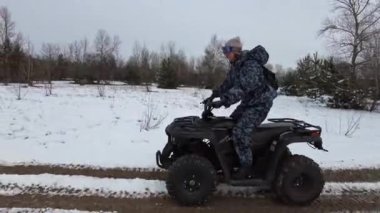 Woman riding on a quad bike on a snow-covered path in winter. ATV bike ride through the snowy landscape. Riding a four-wheeled ATV in a snowy area. Winter vacation. Off-road racing. Lifestyle 4K 50fps